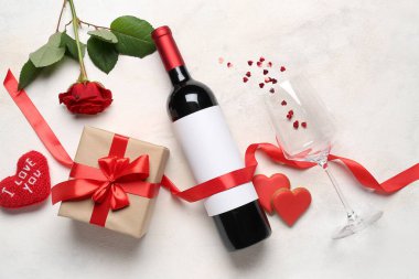 Bottle of wine, gift box, rose flower and heart with text I LOVE YOU on white table. Valentine's Day celebration
