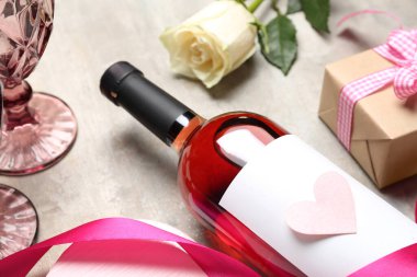 Bottle of wine, rose flower and paper heart on grey table. Valentine's Day celebration