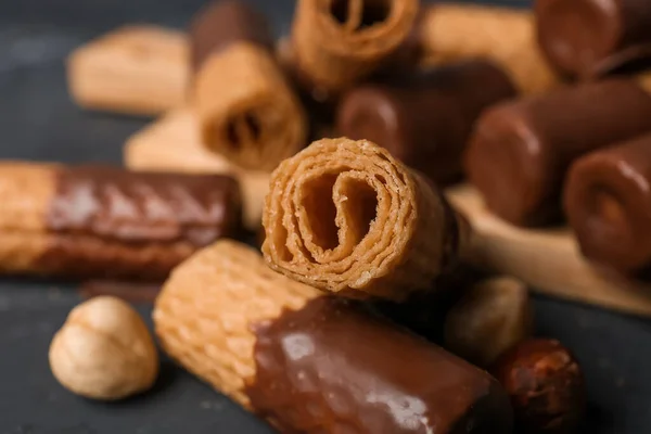 Delicious wafer rolls and hazelnuts on grunge background, closeup