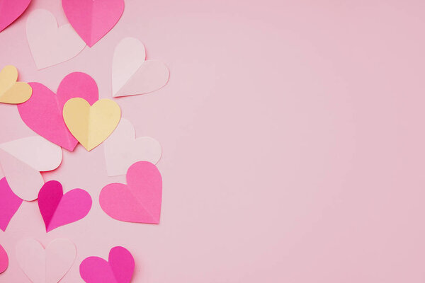 Состав с бумажными сердцами на розовом фоне. Празднование Дня Святого Валентина