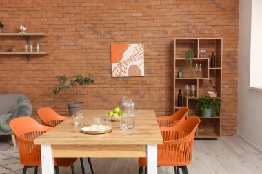 Dining table with water, apples and orange chairs in modern room