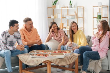 Group of friends with pizza spending time together in living room