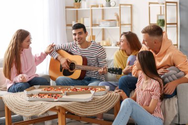 Young man playing guitar for his friends in living room