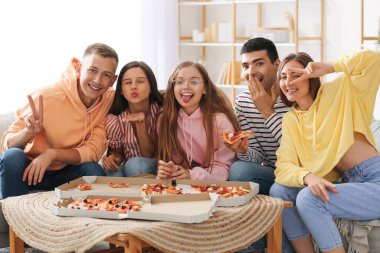 Group of friends with pizza having fun in living room