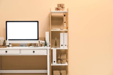 Ofiste bej duvarın yanında bilgisayar ve Noel dekoru olan bir işyeri