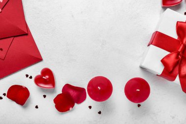 Composition with beautiful candles, gift box and envelopes on light background, closeup. Valentine's Day celebration
