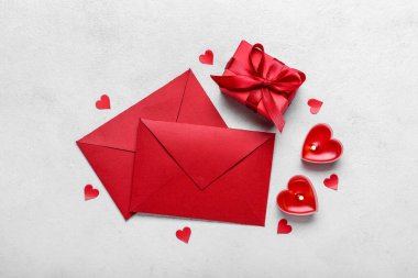 Composition with burning candles, gift box and envelopes on light background. Valentine's Day celebration