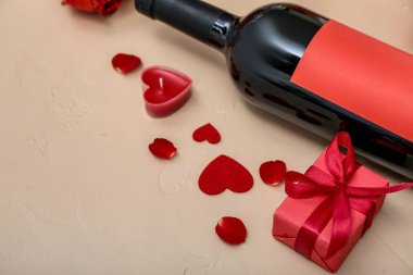 Gift box, bottle of wine and candle on color background, closeup. Valentine's Day celebration