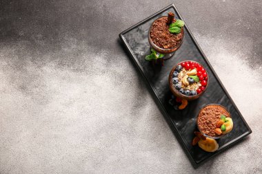 Board with glasses of various chocolate pudding on black and white table