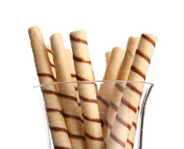 Glass of tasty wafer rolls on white background