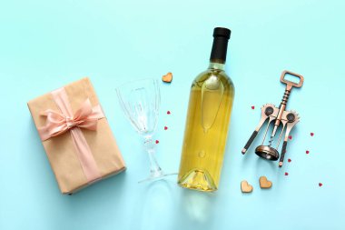 Composition with bottle of wine, glass, gift and corkscrew on color background. Valentines Day celebration