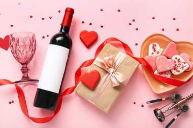 Composition with bottle of wine, glass, cookies and gift for Valentines Day on pink background