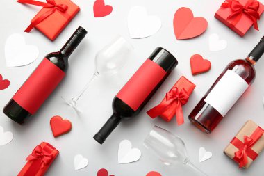 Composition with bottles of wine, glasses, decor and gifts for Valentines Day celebration on light background