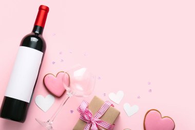 Composition with bottle of wine, glass, cookies and gift box on pink background. Valentines Day celebration