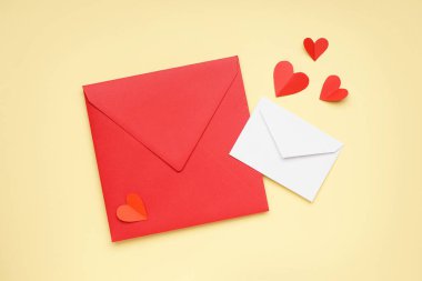 Composition with envelopes and paper hearts on color background. Valentines Day celebration