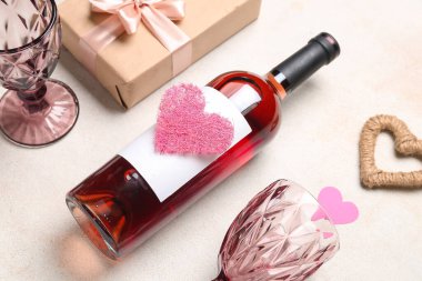 Composition with bottle of wine, glasses, gift and hearts on white grunge background. Valentine's Day celebration