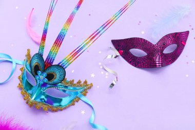 Carnival masks with confetti and serpentine on lilac background