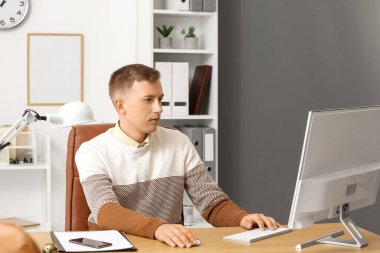 Young businessman working with computer at desk in office