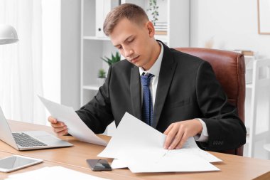 Handsome businessman working with papers at desk in office