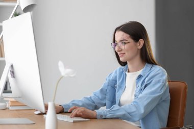 Young woman using computer at table in office