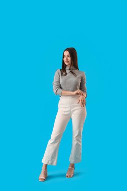 Young woman in grey sweater on blue background