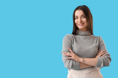 Young woman in grey sweater on blue background