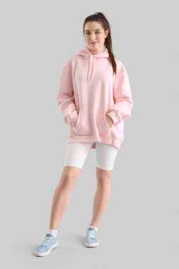 Young woman in pink hoodie on light background