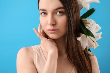 Young woman with white lilies on blue background, closeup