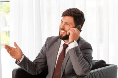 Ofiste cep telefonuyla konuşan yakışıklı iş adamı.