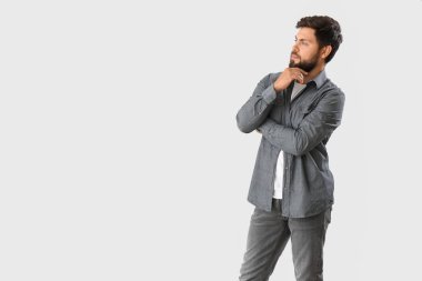 Thoughtful young businessman on light background