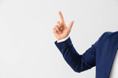 Young businessman pointing at something on light background