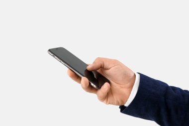 Young businessman using mobile phone on light background, closeup