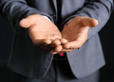 Young businessman showing something on black background, closeup