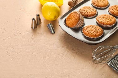 Tray with tasty muffins, lemon and utensils on color background