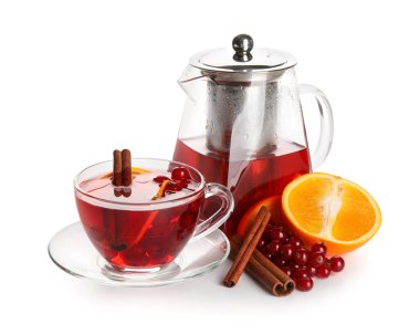 Glass cup of fruit tea with red currant, cinnamon, orange and teapot on white background