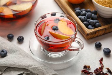 Glass cup of fruit tea with blueberries, apple and peach on white background, closeup