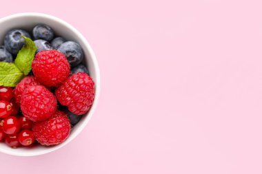 Bowl of fresh ripe berries on pink background