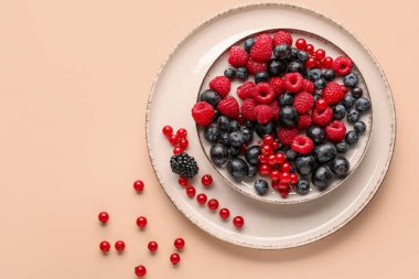 Plate with fresh berries on color background