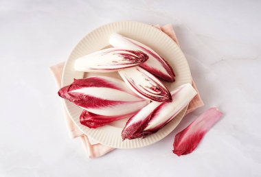 Plate with fresh red endive on light background