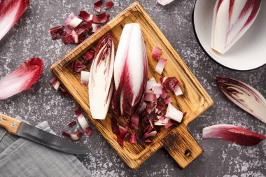 Wooden board with cut red endive on grunge background
