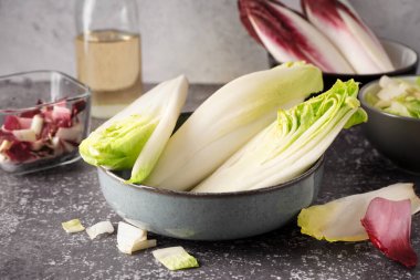 Bowl of cut fresh endive on table clipart