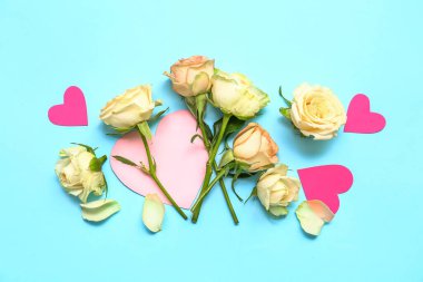 Composition with beautiful rose flowers and paper decor on color background