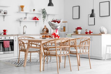 Interior of kitchen decorated for Valentine's Day with flowers, dining table and counters