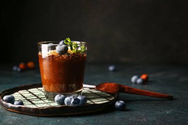Plate with glass of delicious chocolate pudding, blueberry and almond on black table