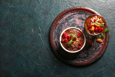 Plate with bowl and glass of delicious chocolate pudding, cranberry and almond on black table