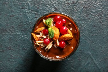 Glass of delicious chocolate pudding, cranberry and almond on black table