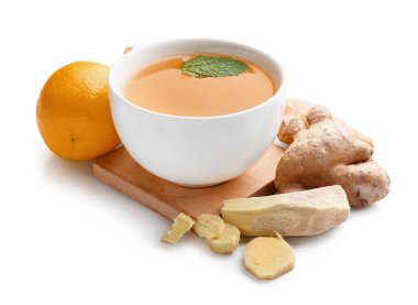 Board with cup of ginger tea, roots, lemon and mint on white background