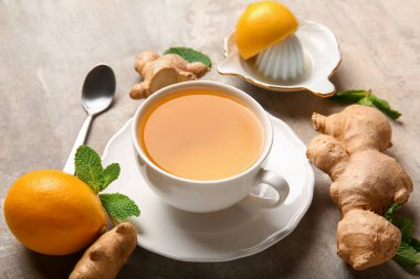Cup of tea, lemon, spoon and ginger on grunge background