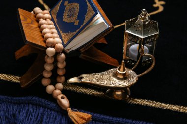 Aladdin lamp, Muslim lantern, Koran and prayer beads for Ramadan on mat, closeup