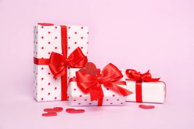 Gift boxes with beautiful bows and hearts on pink background. Valentine's Day celebration